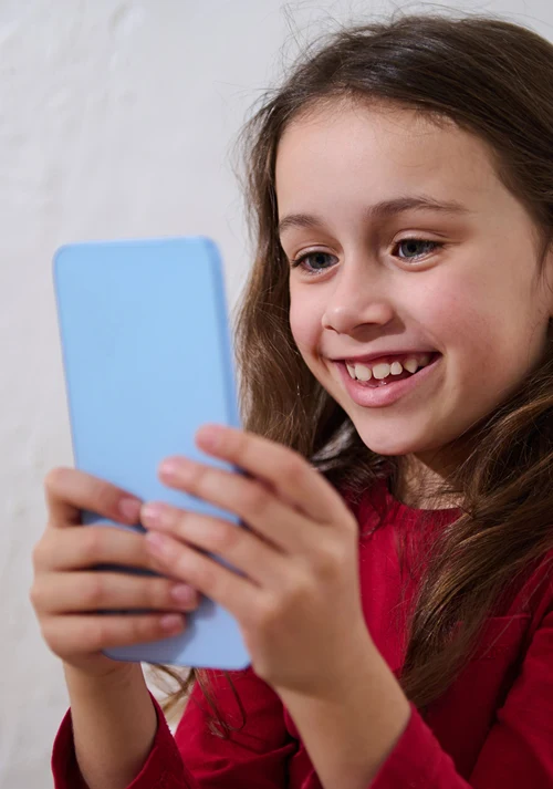 middle school aged girl having a blast as she plays a game on her smartphone.