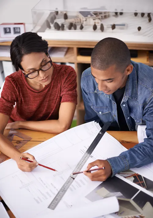 A man and a woman work together at an office table.
