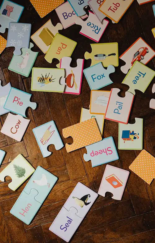 Assorted words on puzzle pieces on wooden floor.