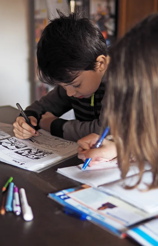 Young boy and girl engaged in work books at home.