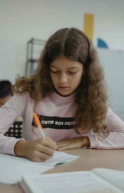 Solemn female student quietly working at classroom desk.