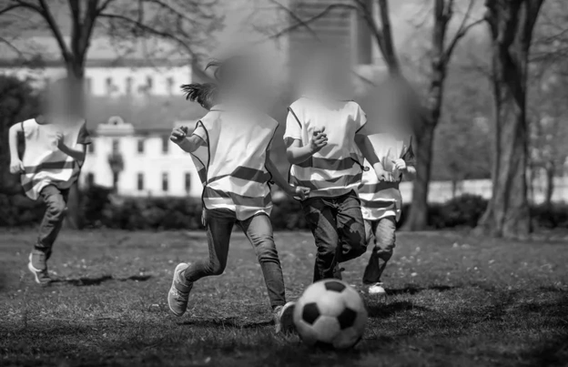 Blurred out faces of kids playing soccer to protect their privacy.