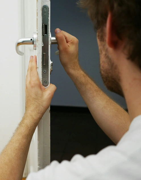 A man holding door in one hand while adjusting the door lever with the other.