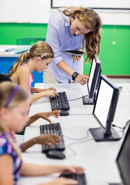 Female teacher in computer class with middle school students.