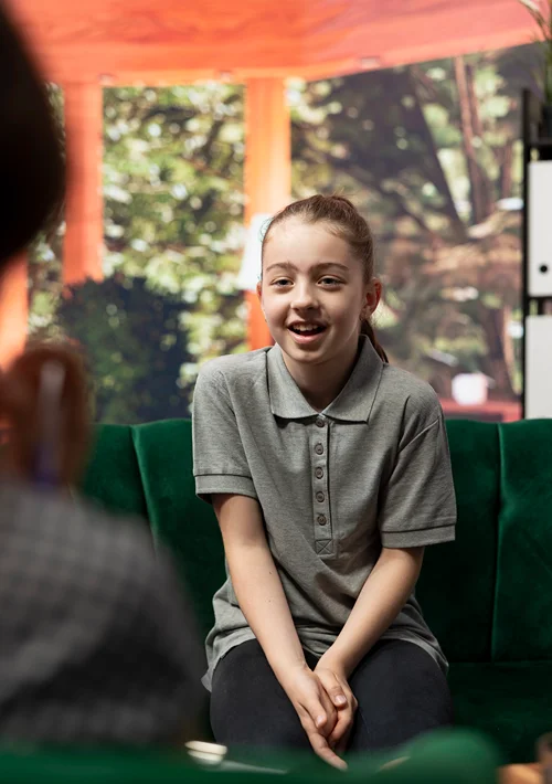 A teen girl smiled as she talks to her therapist in a counseling session.