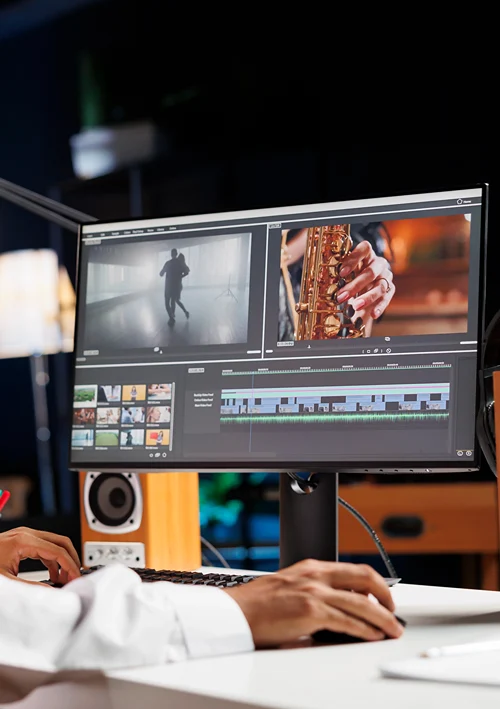 A hand on mouse below a desktop computer screen showing video creation software.