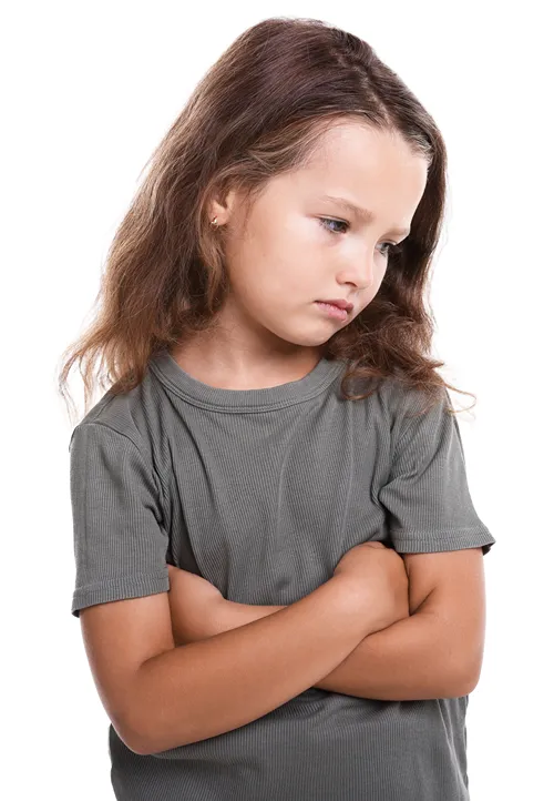 An upset girl crosses her arms and looks downward.