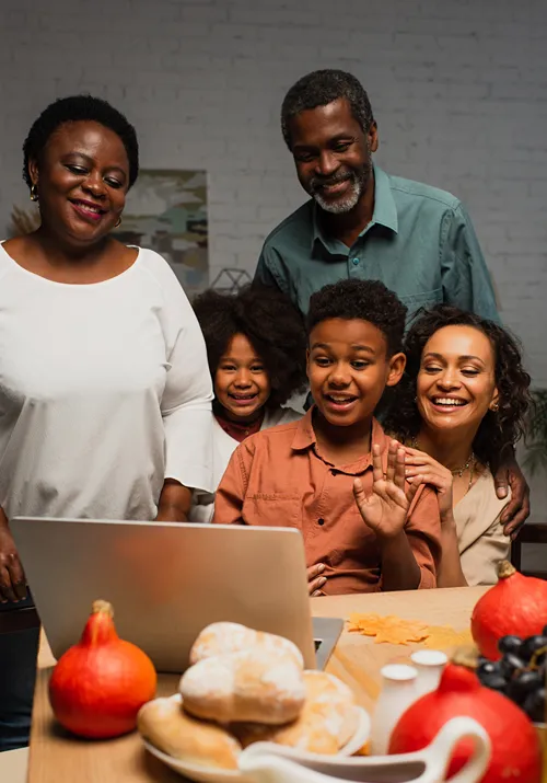 A family gathered around a laptop for a video call.