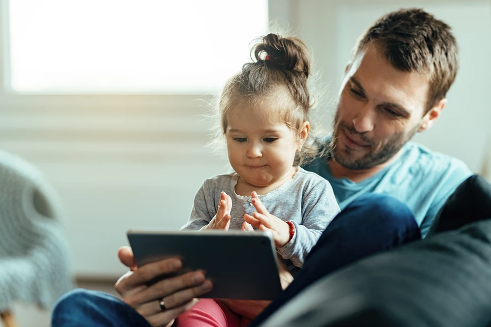 Father and young daughter using a tablet together at home.